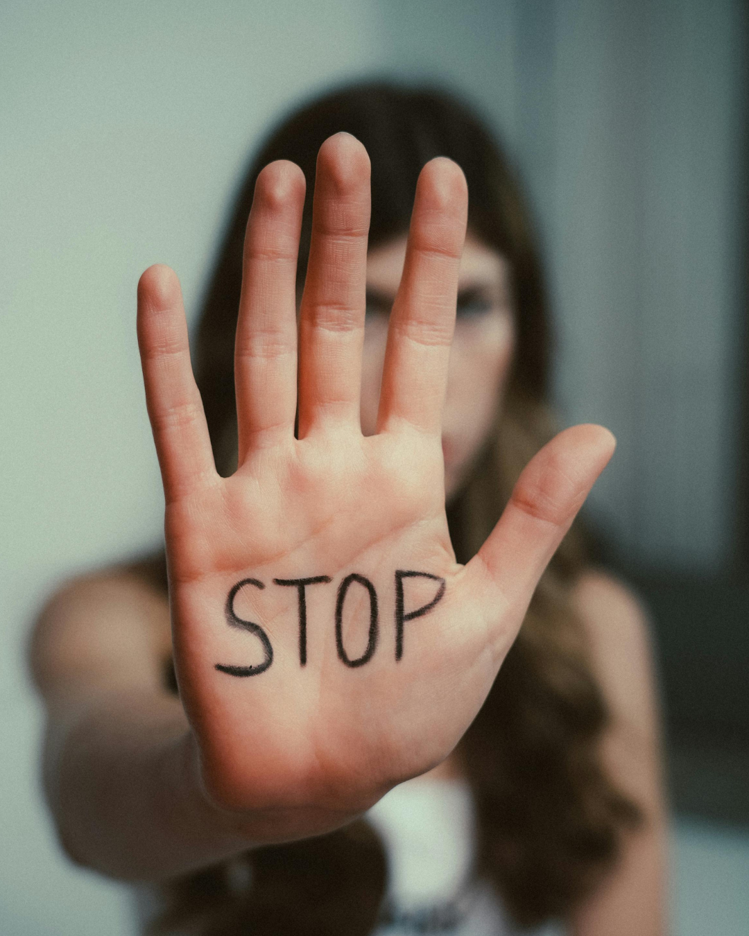 Zu sehen ist die Handfläche einer Frau, die sie Richtung Kamera streckt. Auf die Handfläche hat sie das Wort "Stop" geschrieben.